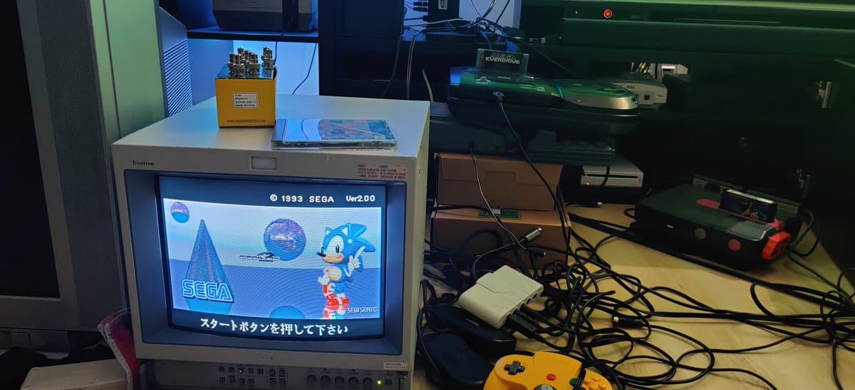 Sega Mega-CD 2 displaying Sonic startup screen on Trinitron CRT monitor after fuse replacement repair; yellow controller and cables visible.