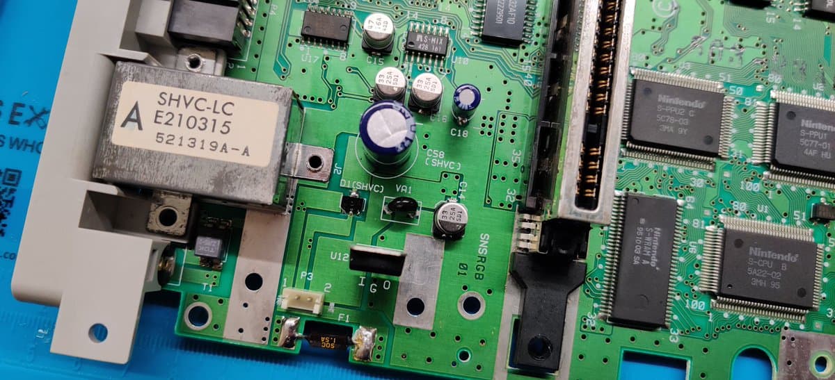 Super Famicom motherboard with SHVC-LC module visible; multiple capacitors and IC chips on green PCB during D1 diode repair work.