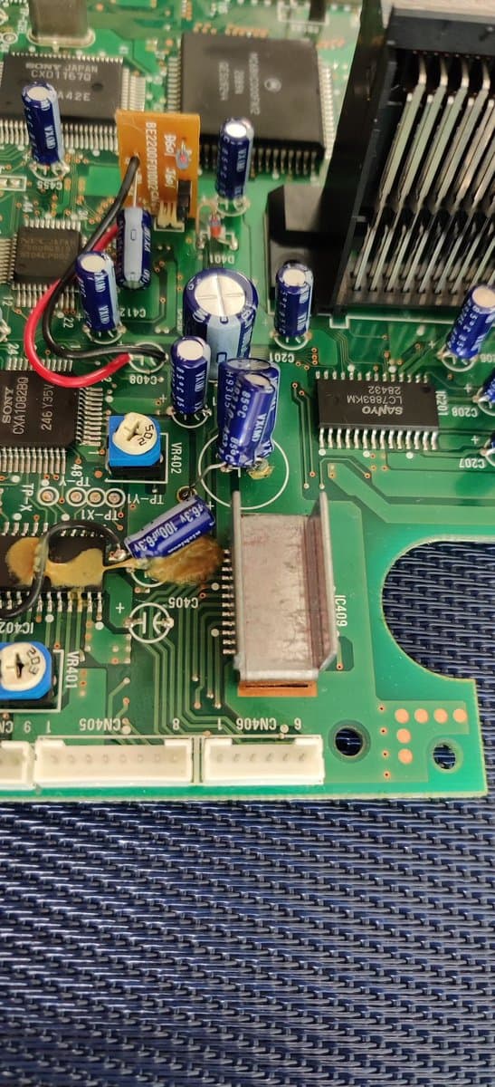 Sega Mega-CD 2 motherboard showing factory bodge wires and electrolytic capacitors before recapping restoration.