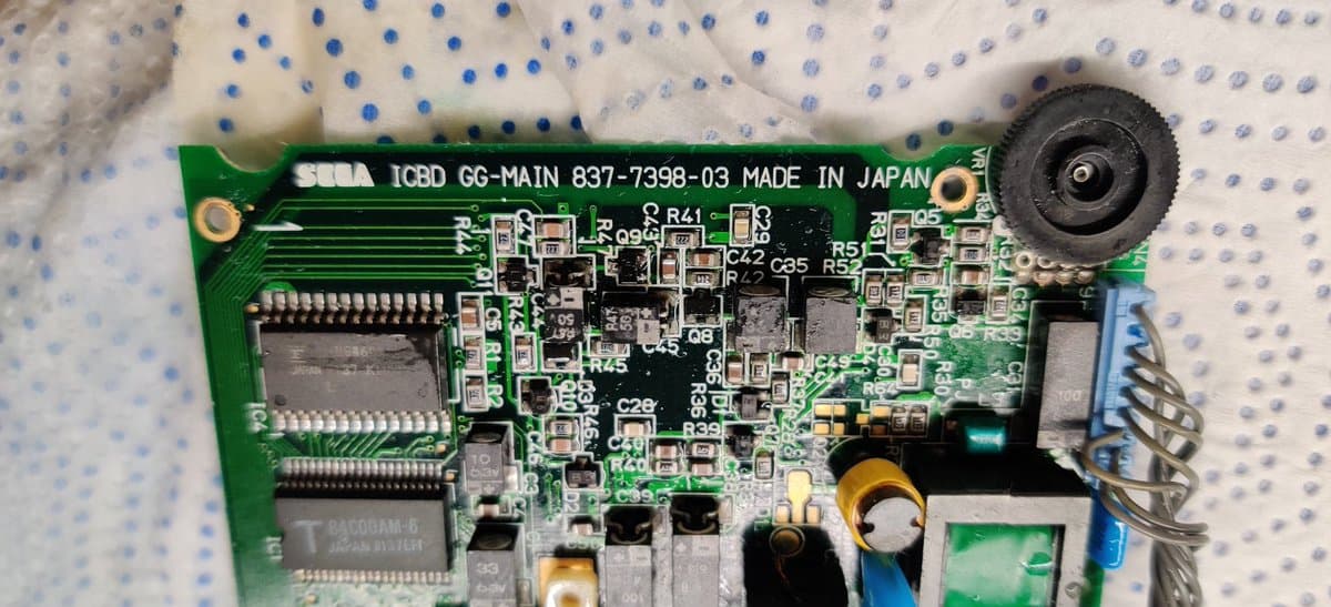Sega Game Gear main board heavily corroded with electrolyte damage, capacitors and components detached from PCB surface.