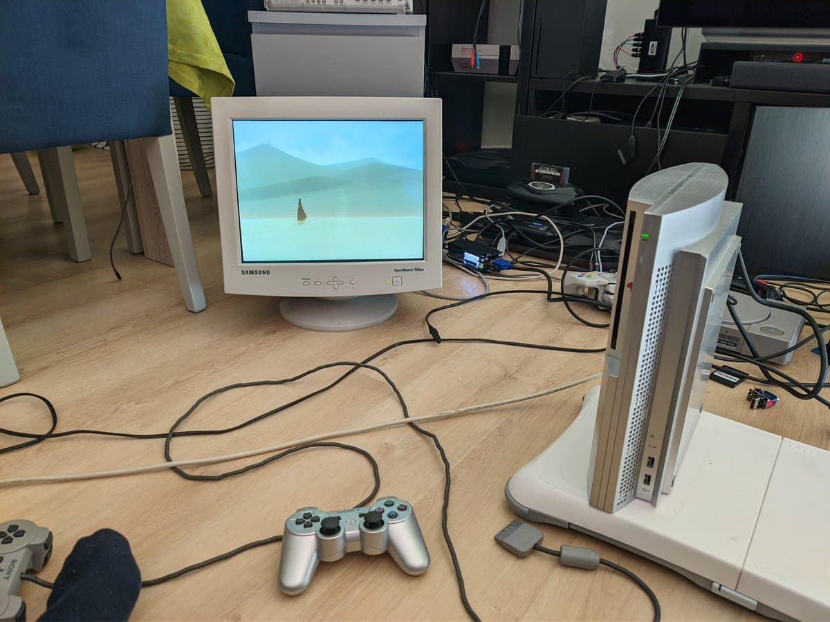 Samsung CRT monitor displaying Journey on PS3, silver controller, white console tower, and cable management on wooden desk workspace.