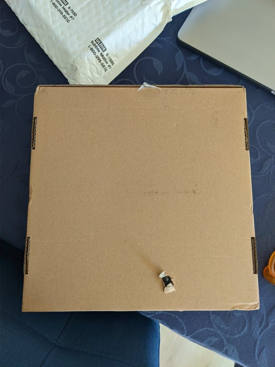 Cardboard Virtual Boy Repair Box with minor damage visible; shows loose connector clip and spring component on interior surface.