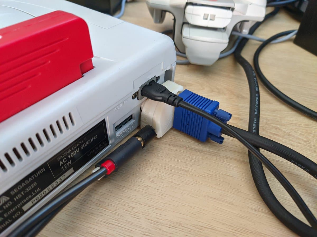 Close-up of a Jeff Chen VGA dongle connected to a white and red console, with blue VGA cable and power adapter visible on wooden desk.