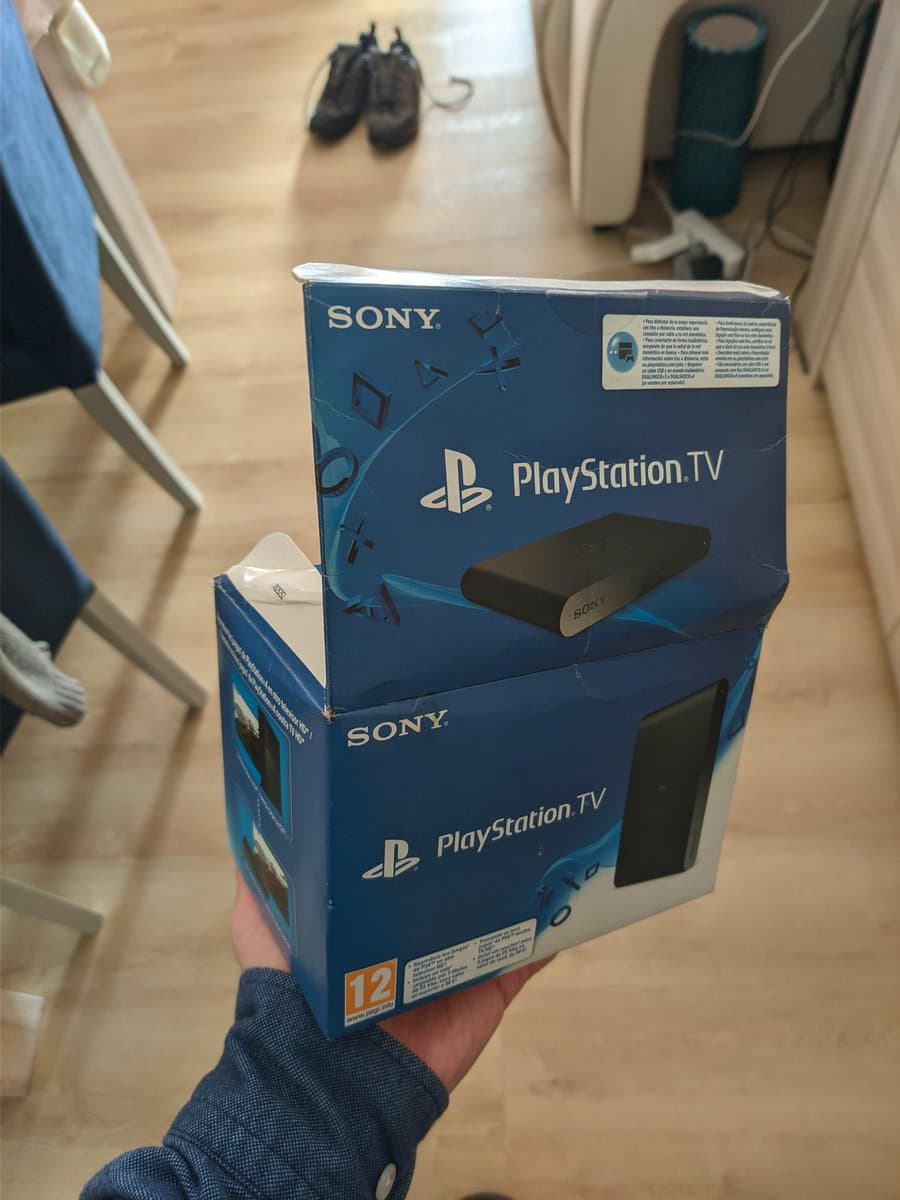 Boxed Sony PlayStation Vita TV held in hand, showing retail packaging with visible mold damage noted in repair notes.