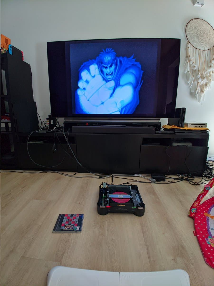 Panasonic FZ-1 3DO console displaying Street Fighter II on TV, with laser module and chess game visible on floor during testing phase of restoration.