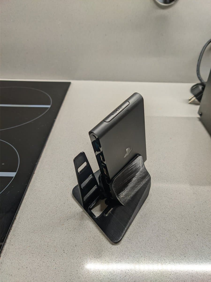 Sony PS Vita TV mounted on black Jeff Chen stand on workbench, showing restored unit after cleaning and CFW installation.