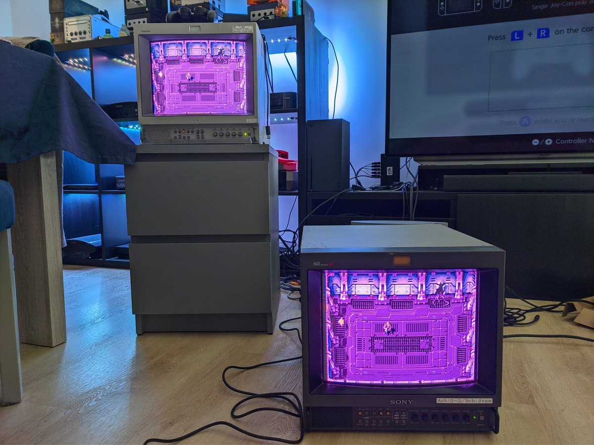 Sony PVM-14M4J displaying magenta test pattern with retrace lines visible; second PVM in background shows same pattern for comparison testing.