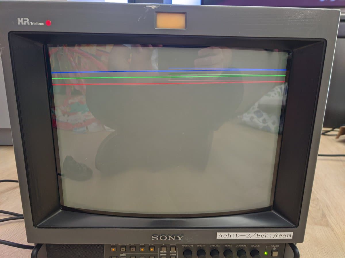 Sony PVM-14M4J CRT displaying horizontal retrace lines across screen; faint image visible beneath with color issues evident.