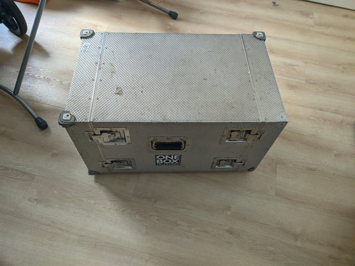 Silver flight case with "ONE" branding on wooden floor, containing Sony BVM-D14H1E professional CRT monitor during restoration.