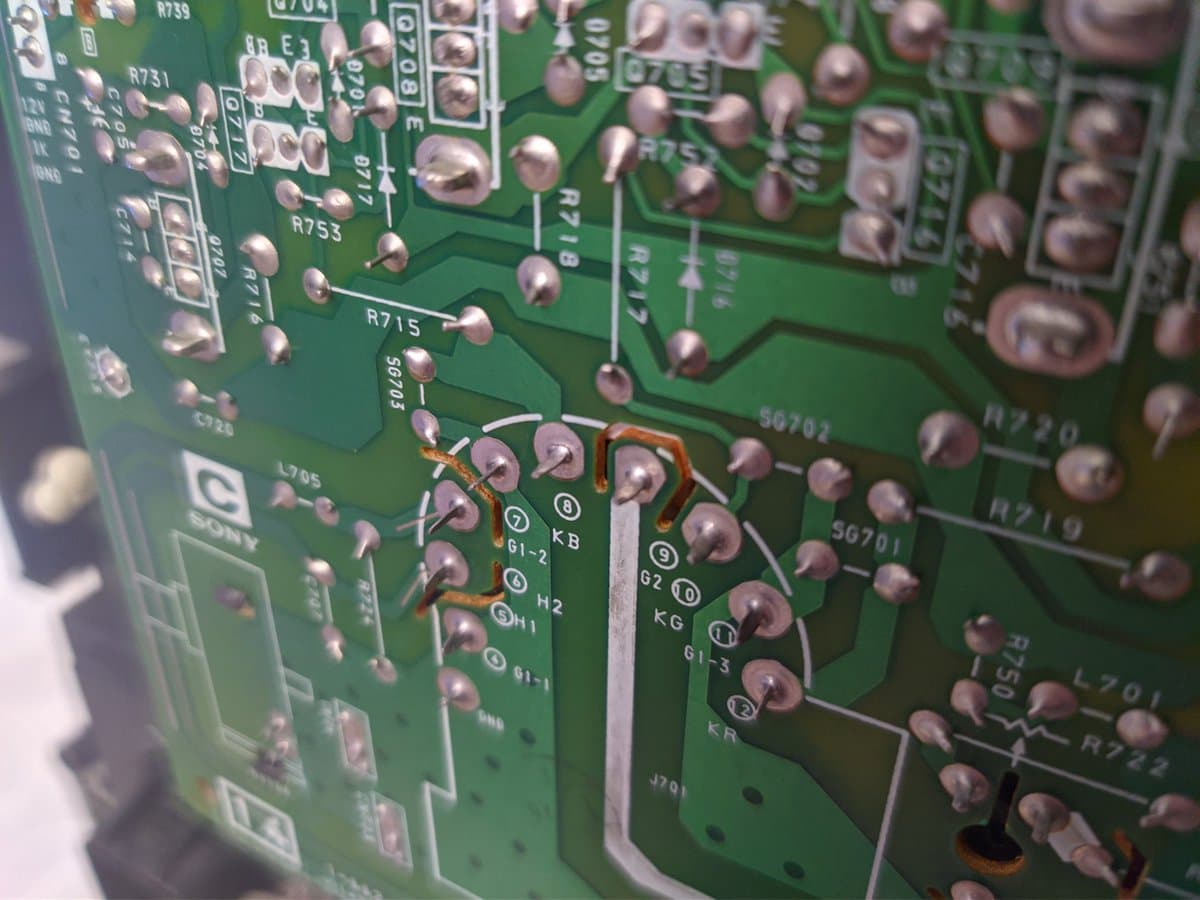 Close-up of Sony PVM-14M4J C board showing broken solder joint at KB tube pin with multimeter probe testing connections.