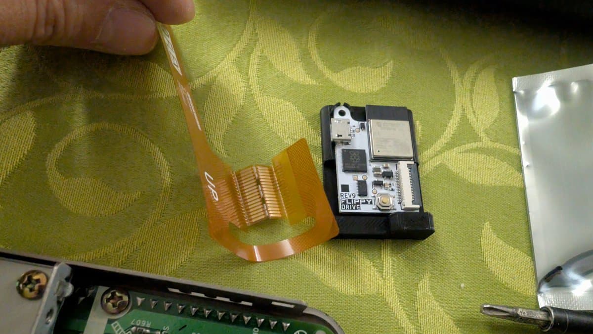 FlippyDrive optical drive assembly with reversed flex cable orientation compared to standard GameCube, displayed during Panasonic Q installation testing.