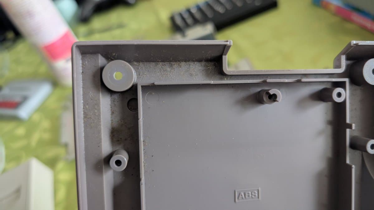 AV Famicom motherboard interior showing ABS plastic housing with mounting posts and connector areas during cleaning and recap maintenance.