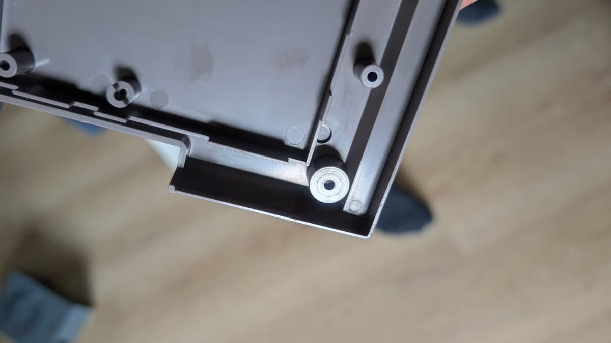 Close-up of recapped AV Famicom motherboard showing new capacitors installed, with multiple mounting holes visible on the gray PCB.