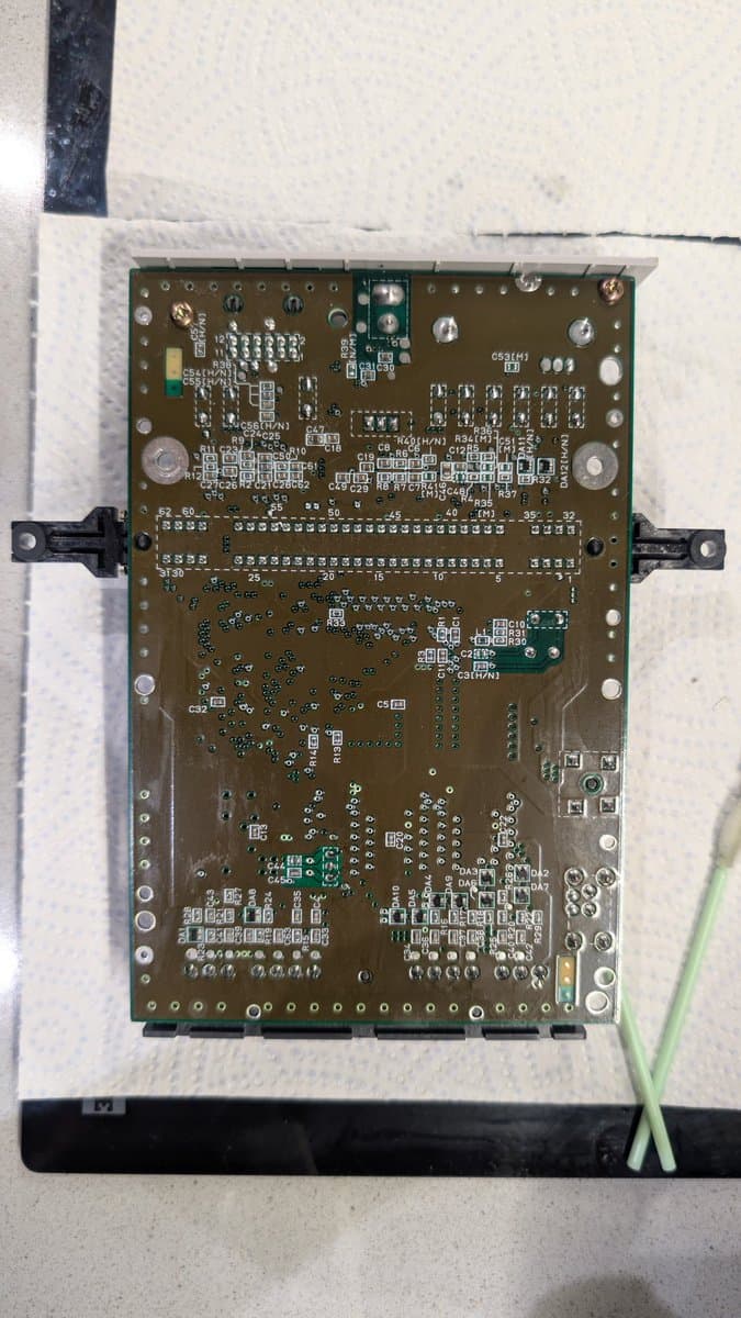 Recapped Super Famicom Jr. motherboard with new voltage regulator, clean solder joints, and organized component layout on work surface.