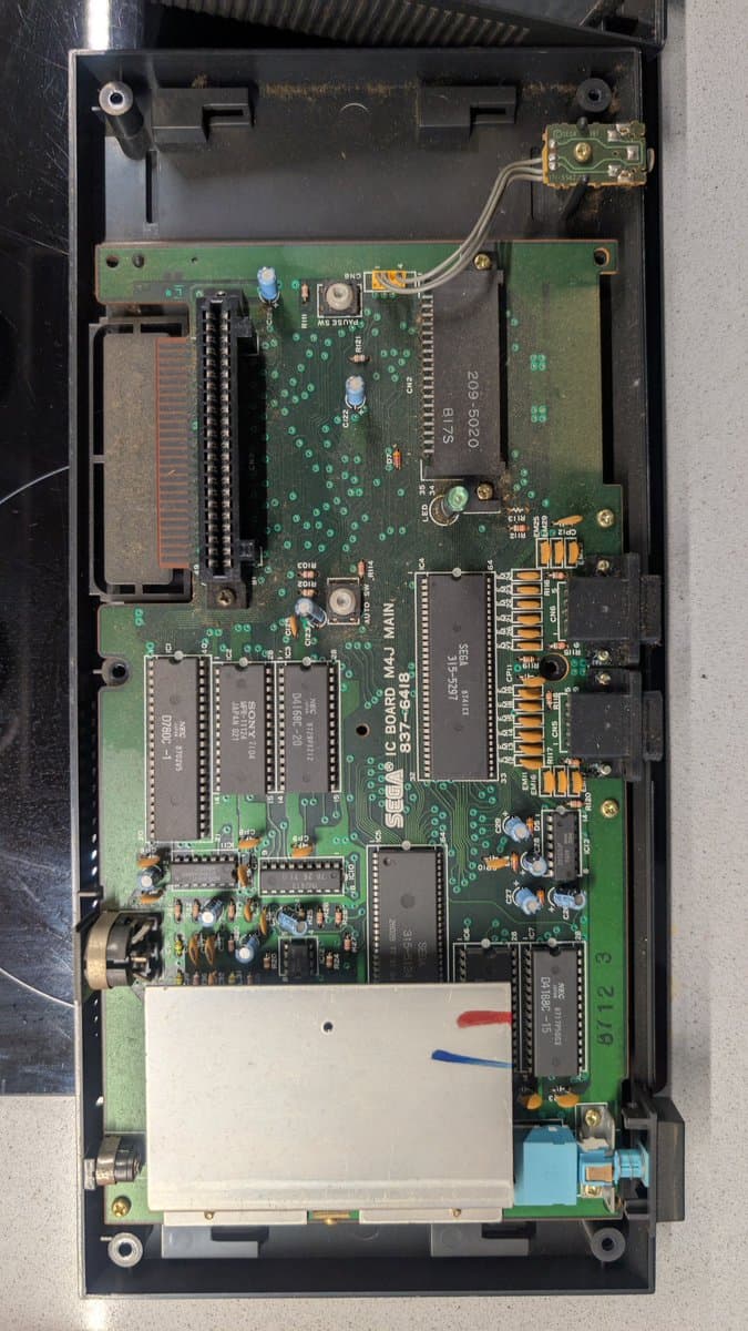 Interior of Sega Master System MK-2000 showing main PCB with multiple ICs, capacitors, and connector ports during refurbishment.