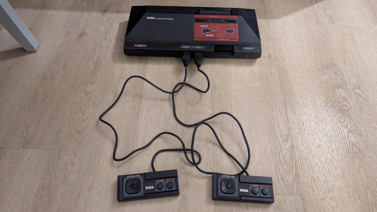 Refurbished Sega Master System MK-2000 with two cleaned Control Pads connected via cables, ready for testing.
