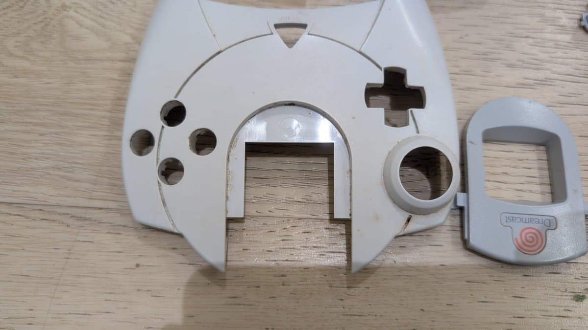 Disassembled Dreamcast controller shells showing internal cavity and button mechanisms during cleaning refurbishment process.