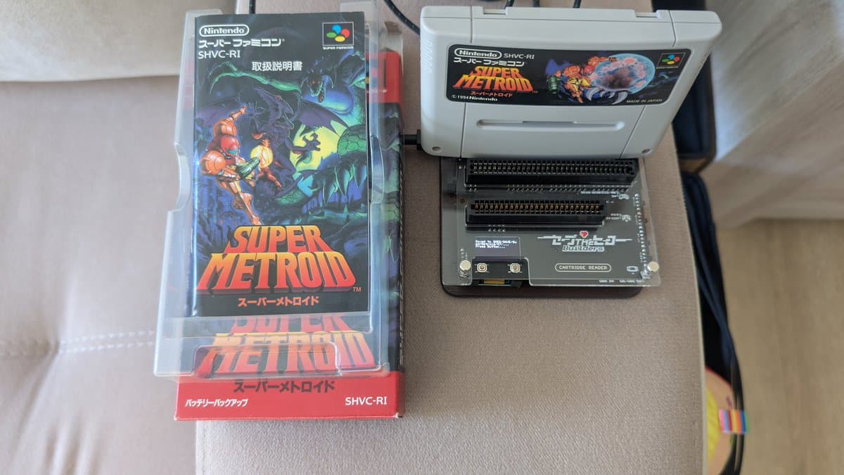 Super Metroid cartridge next to open SNES console showing cartridge slot and internal components during battery replacement maintenance.