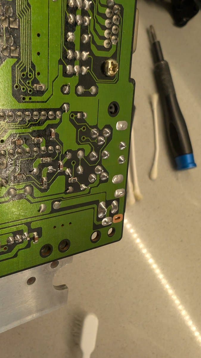 Sega Mega Drive mainboard being resoldered with iron; power and AV connector joints touched up during final prep before shipment.