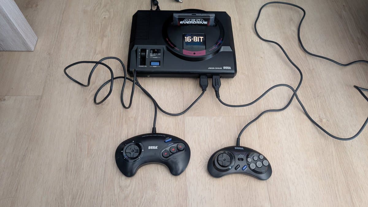 Sega Mega Drive 16-Bit console with two cleaned controllers and cables on wooden surface, ready for delivery.