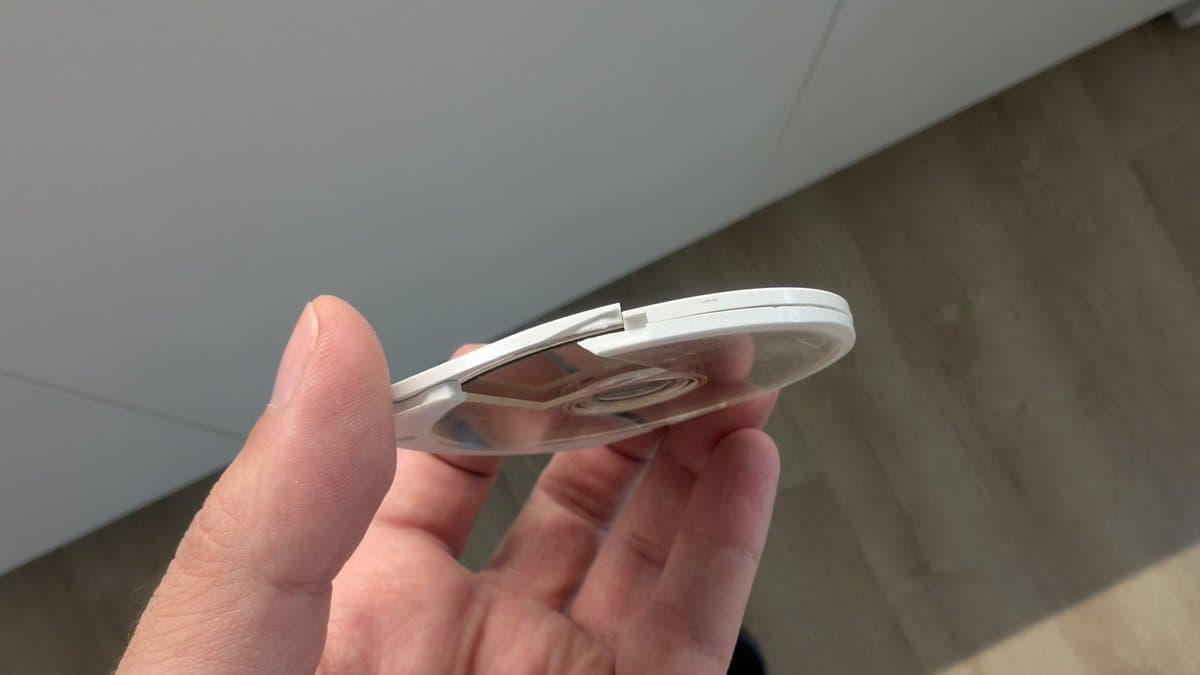 Hand holding PSP with visible crack across screen lens, white border frame damaged.