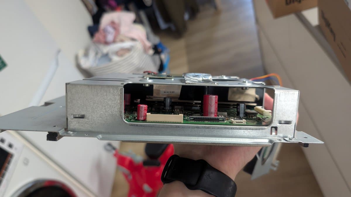 Asus PG27UQ monitor mainboard with red CapXon capacitors replaced by Nichicon and Würth capacitors, held in hand during refurbishment.