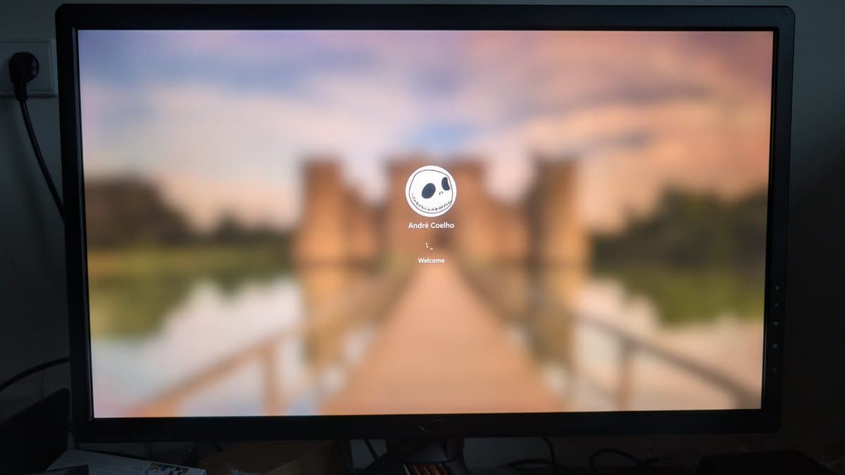 Asus PG27UQ monitor displaying boot screen with "André Coelho" user profile and "Welcome" text during post-repair startup verification.