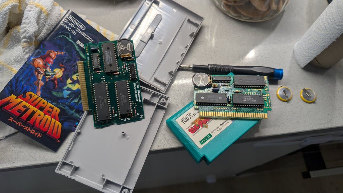Disassembled Super Metroid and Zelda cartridge PCBs showing replaced coin cell battery holders and capacitors during maintenance repair work.