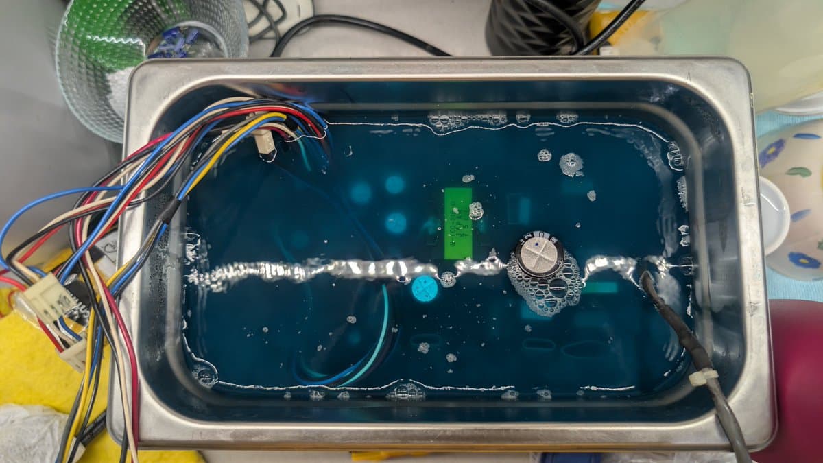 Sharp X68000 PSU capacitor measurement showing failed component; multicolored wires and silver cylindrical capacitor visible in metal enclosure.