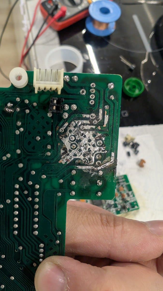Close-up of Sharp X68000 PCB showing repaired broken trace with solder joint patching and connector header during restoration work.
