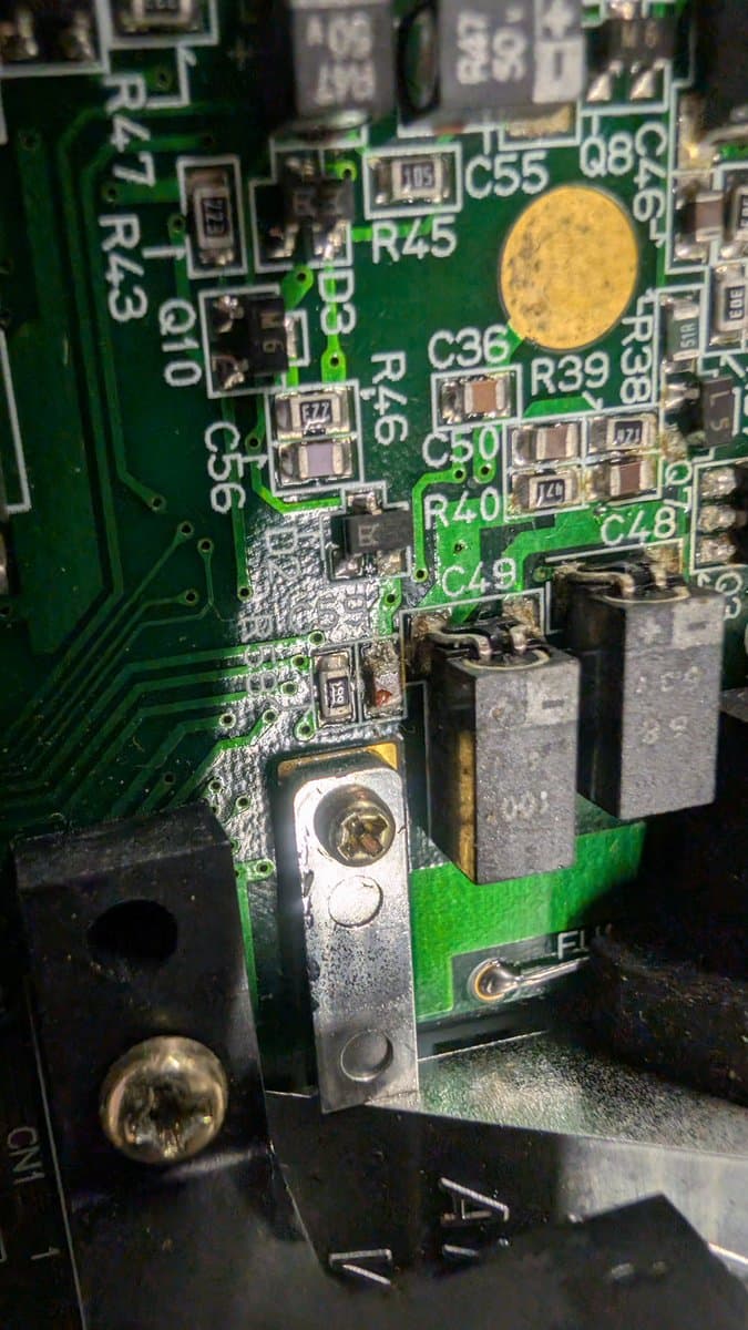 Close-up of Game Gear PSU board showing corroded capacitors, damaged solder joints, and dangerous bodge wiring—fire hazard evident.