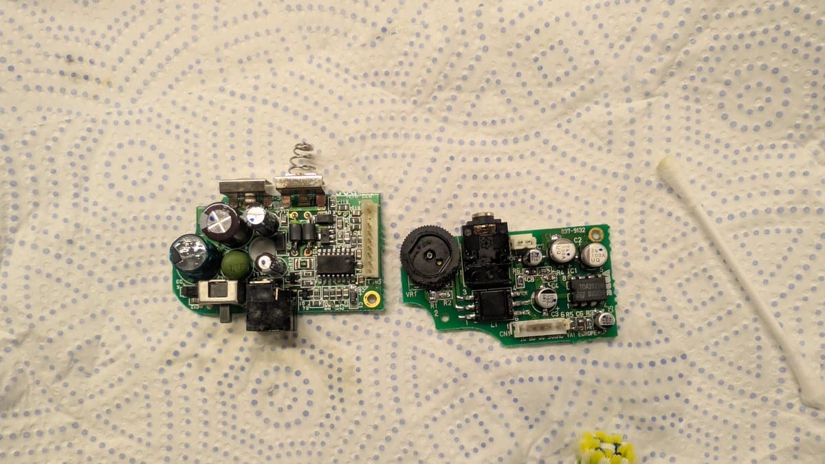 Two Sega Game Gear circuit boards after recapping and solder reflow repair, showing replaced capacitors and reworked solder joints.