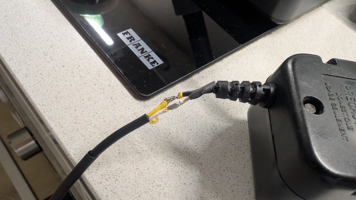 Close-up of repaired Game Gear power cable with heat shrink tubing layers around soldered wire connections and strain relief.