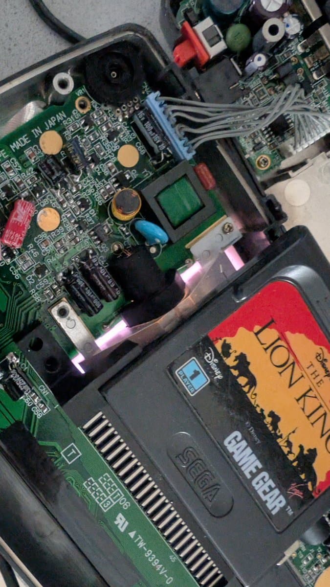 Game Gear motherboard with exposed CCFL backlight assembly and internal components during bulb replacement repair.