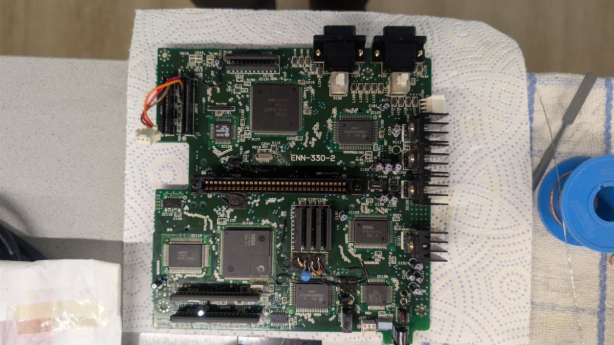 Sega Wondermega ENN-530-2 Mega Drive board during recapping and regulator cleaning, showing exposed circuitry and components on work surface.