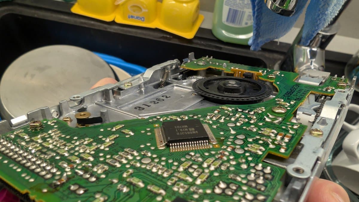 Fujitsu FM Towns Marty floppy drive PCB during recap; visible IC chip, solder joints, and motor assembly with spindle exposed.