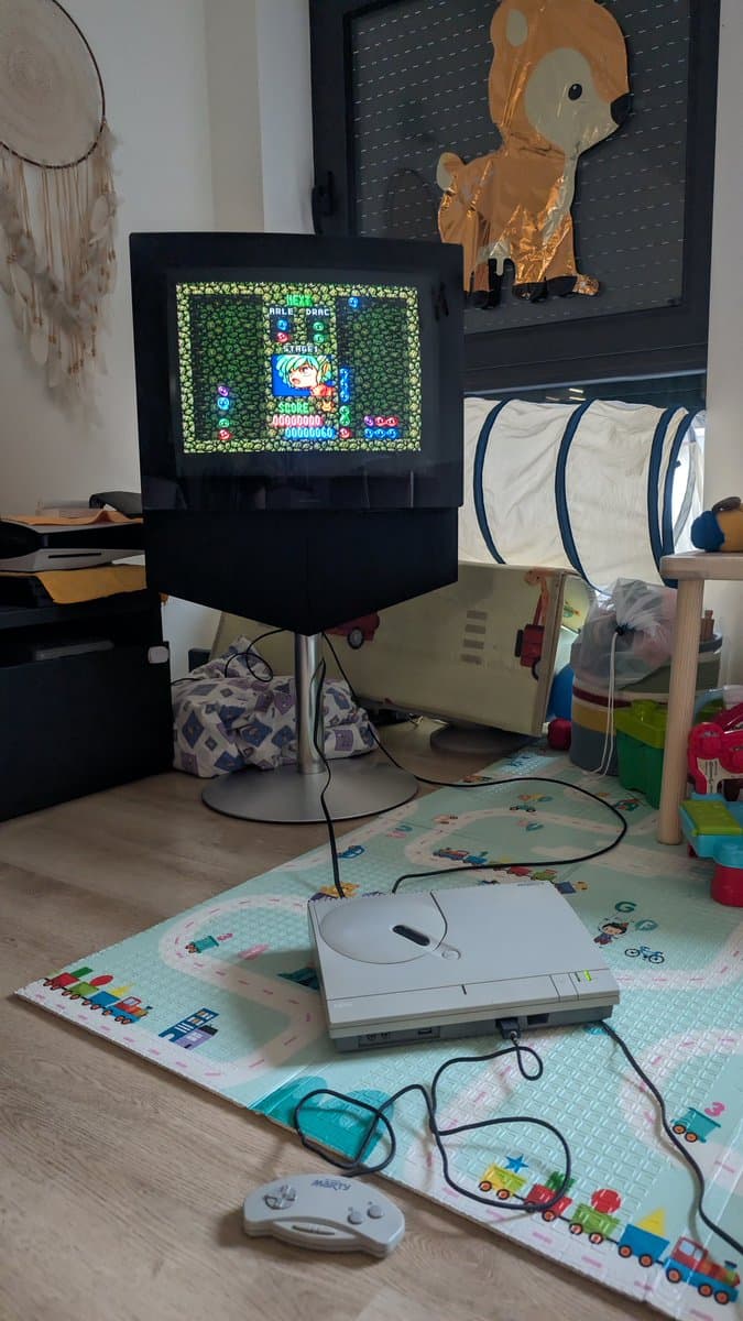 FM Towns Marty console displaying Puyo Puyo on CRT monitor, with replacement capacitors installed in PSU, floppy drive awaiting new belt repair.