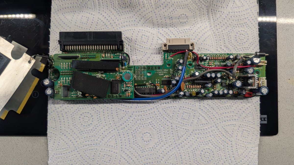 PC Engine IFU-30 main board after recap: new capacitors, voltage regulator, and supercapacitor installed; soldering iron visible on left.