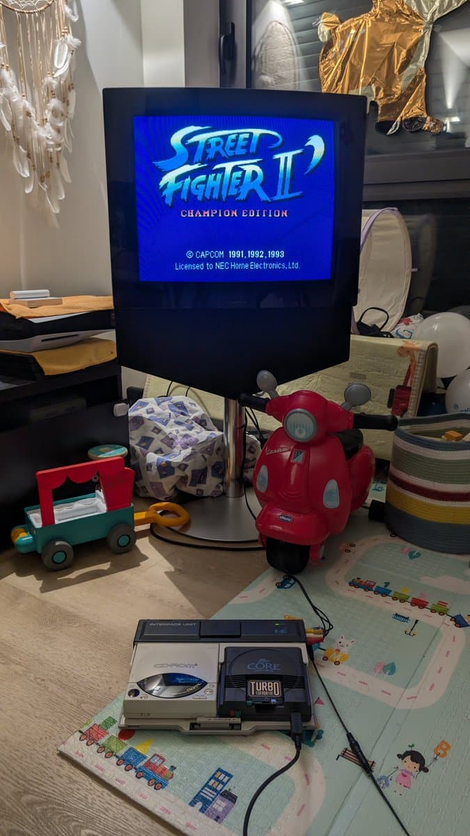 NEC PC Engine IFU-30 displaying Street Fighter II Champion Edition on CRT monitor, with recapped console and controller below on workbench.