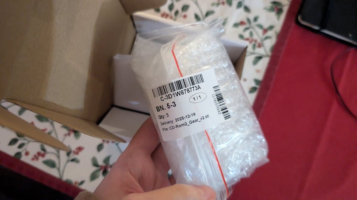 Close-up of packaged 3D printed gear component for PC Engine CD-ROM2 sled mechanism, labeled with barcode and delivery date 2025-12-19.