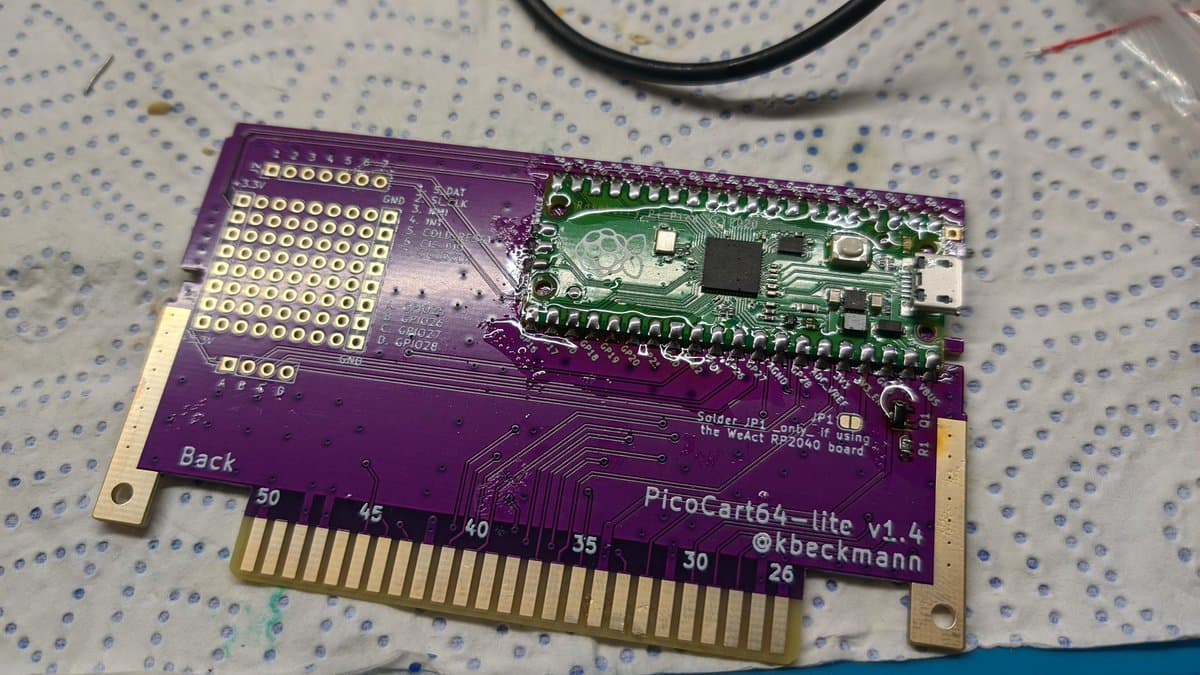 PicoCart64 lite v1.4 PCB assembly showing purple circuit board with Raspberry Pi Pico microcontroller and gold-plated N64 cartridge connector.
