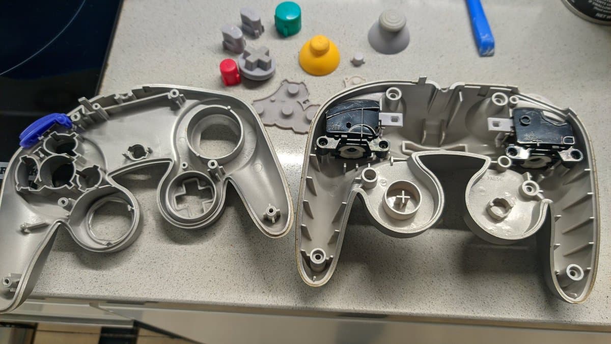 Disassembled controller shells and internal components laid out after ultrasonic cleaning, showing cleaned plastic parts and small hardware pieces.