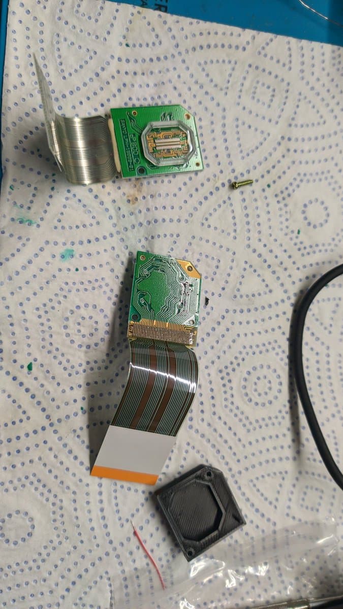 Disassembled Virtual Boy display components showing LED array PCBs with attached flex ribbons in various stages of separation and removal during refurbishment.