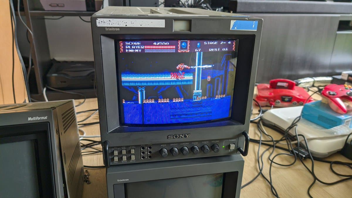 Sony PVM-9041Q displaying Castlevania gameplay during restoration testing; Trinitron monitor stacked above with game controllers nearby on workbench.