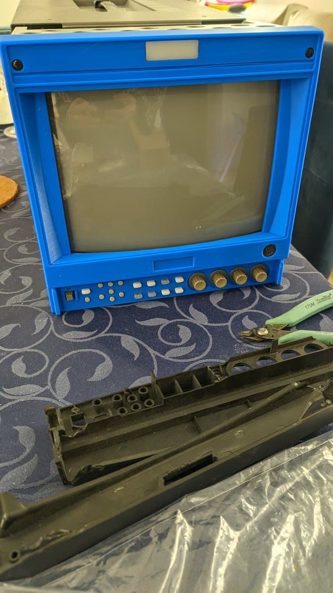 Bright blue Ikegami HTM-1005RA2 CRT monitor with disassembled bezel and internal components displayed below, alongside repair tools.