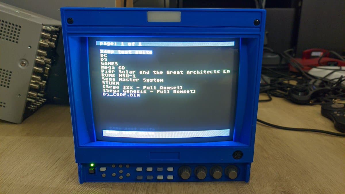 Ikegami HTM-1005RA2 CRT displaying boot menu with game titles listed, blue bezel intact, front controls visible, successful repair completion.