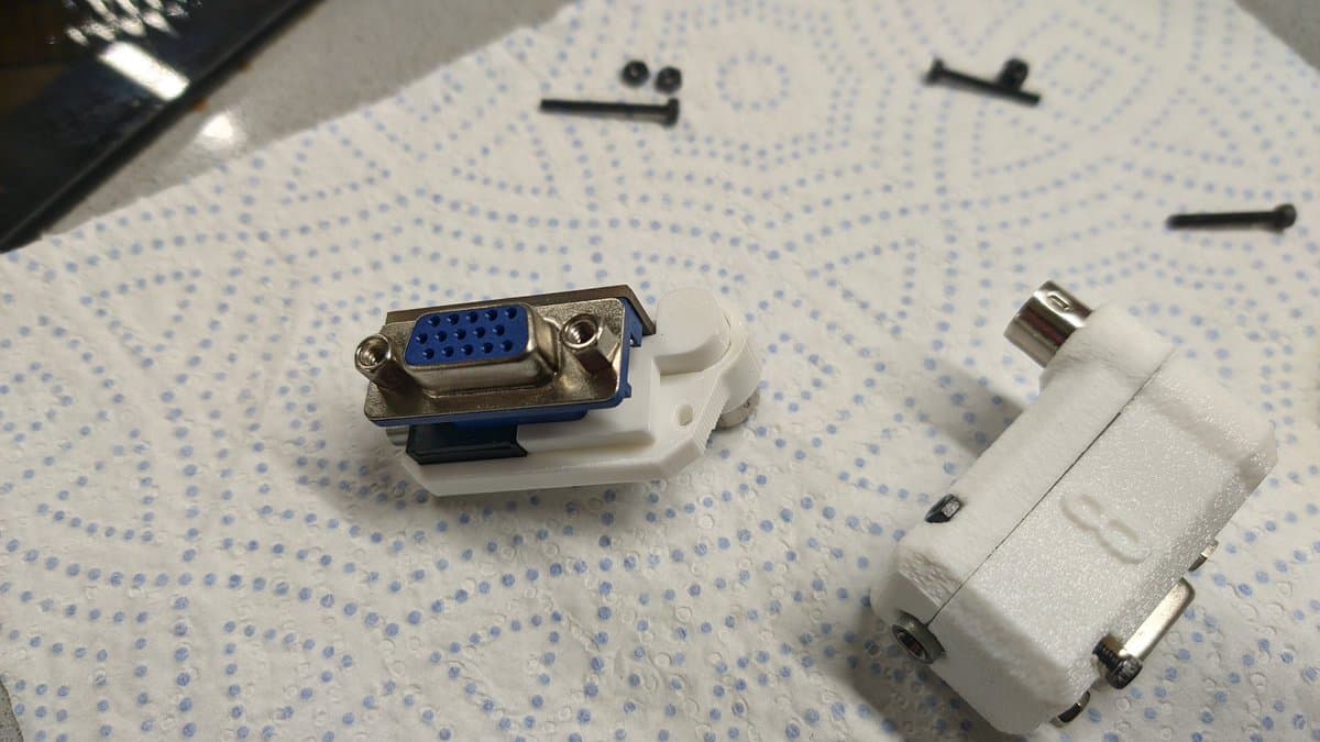 Two white 8DIN to VGA adapter shells with metal DB15 connectors, one assembled with blue pinout visible, on dotted paper.