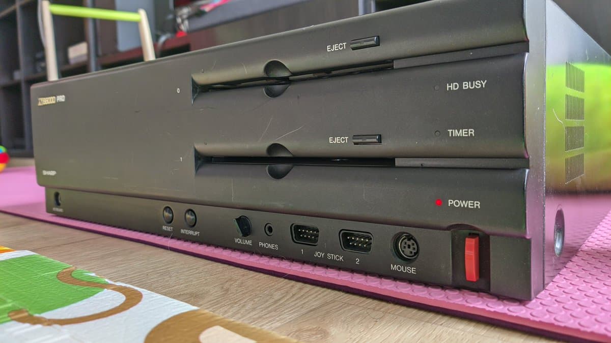 Sharp X68000 Pro II front panel showing dual 3.5" floppy drives with eject buttons, power LED indicator, and I/O ports including joystick and mouse connectors.