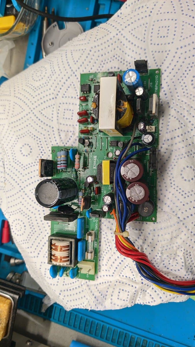 Sharp X68000 Pro II power supply board with reversed capacitor damage, showing electrolytic caps, transformer, and charred component area from magic smoke incident.
