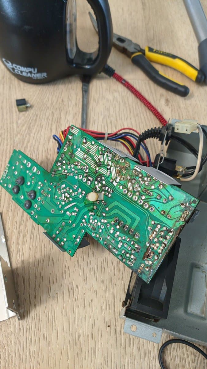 Disassembled Sharp X68000 Pro II PSU board with capacitor debris, corroded solder joints, and failed components alongside screwdrivers and diagnostic tools.